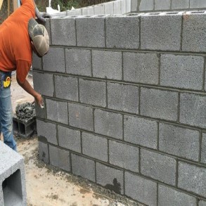 worker installing a block wall using mortar
